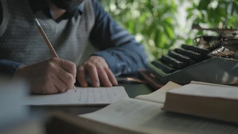 A man writes on paper, typewriter is in front of him Stock Footage 116674033