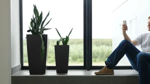 Man writes an SMS and looks out the airport window. The guy is talking in Stock Footage 81561759