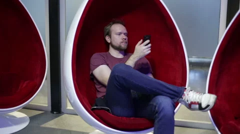 Man writes sms in an egg-shaped chair Stock Footage 58200901