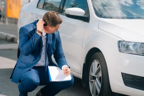 A man writes in a tablet next to the car. An accident on the road, the airbag Stock Photos