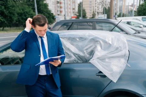 A man writes in a tablet next to the car. An accident on the road, the airbag Stock Photos