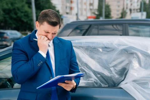 A man writes in a tablet next to the car. An accident on the road, the airbag Stock Photos