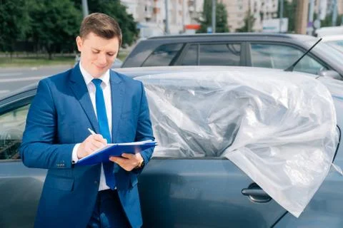 A man writes in a tablet next to the car. An accident on the road, the airbag Stock Photos