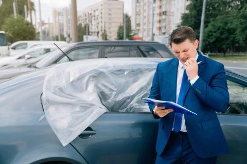 A man writes in a tablet next to the car. An accident on the road, the airbag Stock Photos