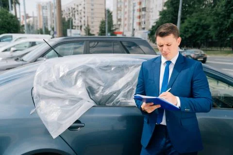 A man writes in a tablet next to the car. An accident on the road, the airbag Stock Photos