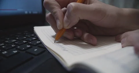 Man writes text in a notebook lying on a laptop Stock Footage 143005392