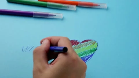 A man writes a wish on paper with a rainbow heart, a symbol of Valentine's Day. Stock Footage 167370797