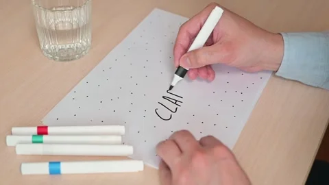 A man writes the word clarity surrounded by dots on a piece of paper 스톡 동영상 337558888