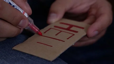 A man writes the word help on a cardboard card with a red felt-tip pen close-up Video stock 190081174