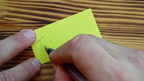 A man writes words of thanks on a yellow sticker with a pen. Slow motion Stock-Footage 286033706