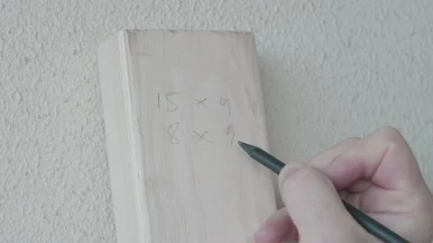 Man is writing 4 different dimensions on wood block with a pencil Stock Footage