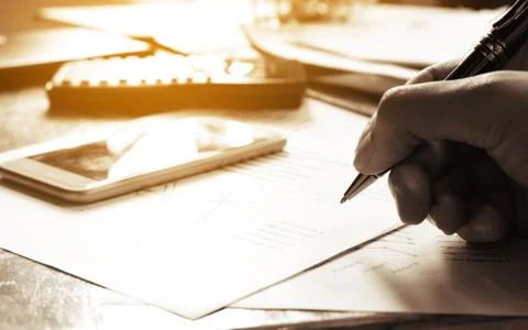Man writing and make note about cost and expenses at office. Stock Photos