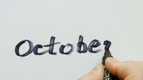 Man is writing a black marker word for october Stock Footage 79850722