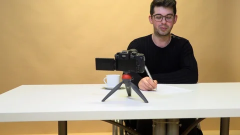 Man writing blog for on internet camera in studio at table and lighting Stock Footage 125333593