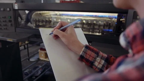 Man writing with blue pen in tablet at work, front of manufactury line. Closeup Stock Footage 110794491