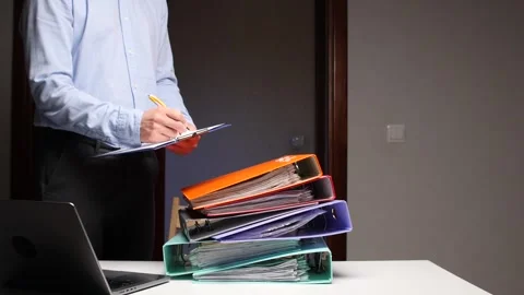Man writing on clipboard near stack of binders Stock Footage 322911729