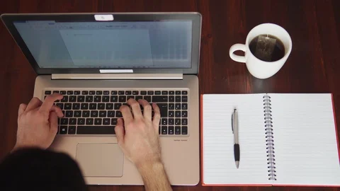 Man writing on the computer and taking notes with pen. View from top Stock Footage 129440901