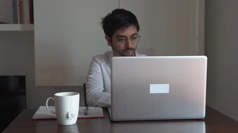 Man writing on the computer and taking notes with pen on the desk Stock Footage 129441293