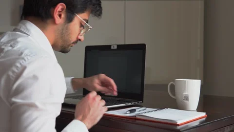 Man writing on the computer and taking notes with pen on the desk Stock Footage 129441509