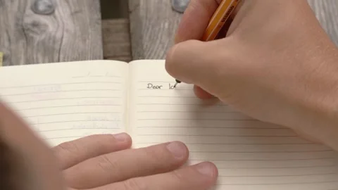 Man writing dear love in notebook on wooden table Stock Footage 312849969