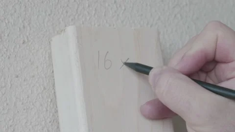 Man is writing different dimensions on wood block with a pencil Stock Footage 146074773