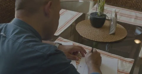 Man writing down a list on the paper at table Stock-Footage 83187152
