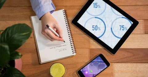 Man writing down notes with digital tablet and smartphone on wooden table Foto stock