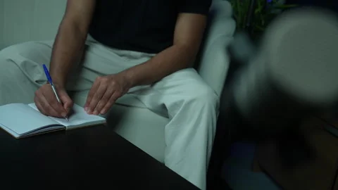 Man writing down notes in a notebook with a pen during a podcast recording Stock Footage 336278516