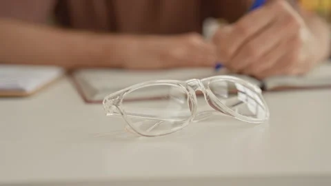 Man writing with hand and blue pen next to clear eyeglasses and open book o.. Stock Footage 337376029