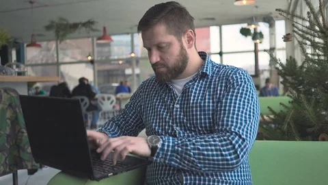 Man writing on laptop computer, in cafe, portrait, steadycam shot 库存影片 72951121