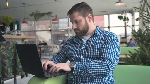 Man writing on laptop computer looking at camera, cafe, portrait, steadicam shot Vidéo 72951143