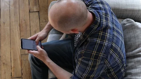 Man writing a message on the phone while sitting on the couch. Stock Footage 254908893