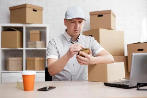 Man writing a note in a notebook at the post office Stock Photos