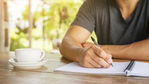 Man writing on a notebook in a cafe. Stock Photos