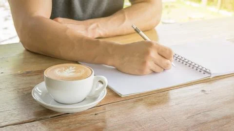 Man writing on a notebook in a cafe. Stock Photos