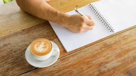 Man writing on a notebook in a cafe. Stock Photos