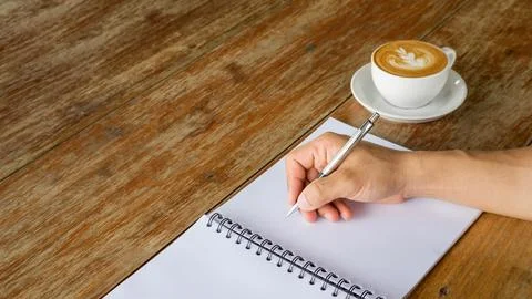 Man writing on a notebook in a cafe. Stock Photos