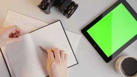 Man Writing in Notebook then Taps Green Screen Tablet in Slowmotion 動画素材 176974915