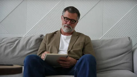 Man writing in notebook white sitting on sofa Stock Footage 278987323