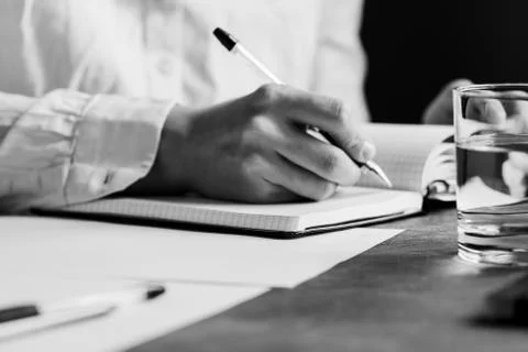 The man is writing in a notebook in a workplace. The concept of a work and ed Stock Photos
