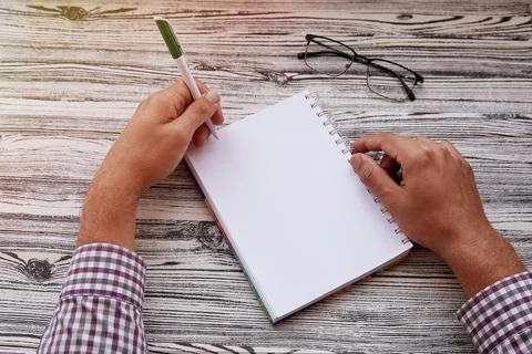 Man writing in notepad, using his left hand. Conceptual photo of lefthanded day Stock Photos