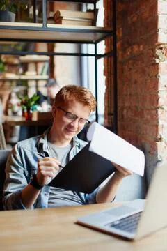 Man writing in the notes he made earlier. Stock Photos