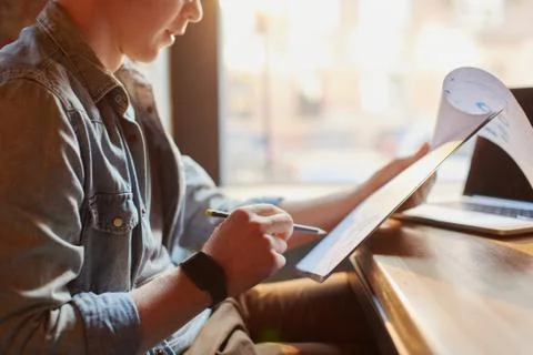 Man writing in the notes he made earlier. Stock Photos