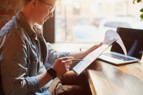 Man writing in the notes he made earlier. Stock Photos