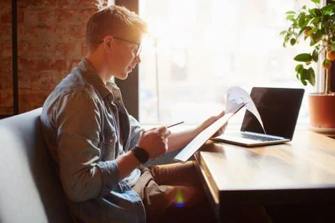Man writing in the notes he made earlier. Stock Photos