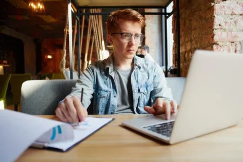 Man writing in the notes he made earlier. Stock Photos