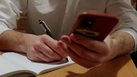 Man writing notes while checking phone 库存影片 342780009