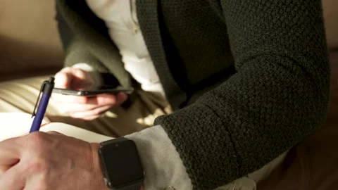 Man writing notes while using phone at home. Stock Footage 264841196