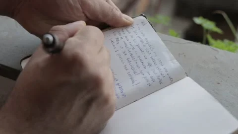 A man writing on the pages from a notebook with a shallow depth of field Stock Footage 167294029