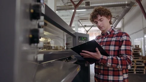 Man writing with pen in tablet at work, front of manufactury line. Closeup of Stock Footage 110794784